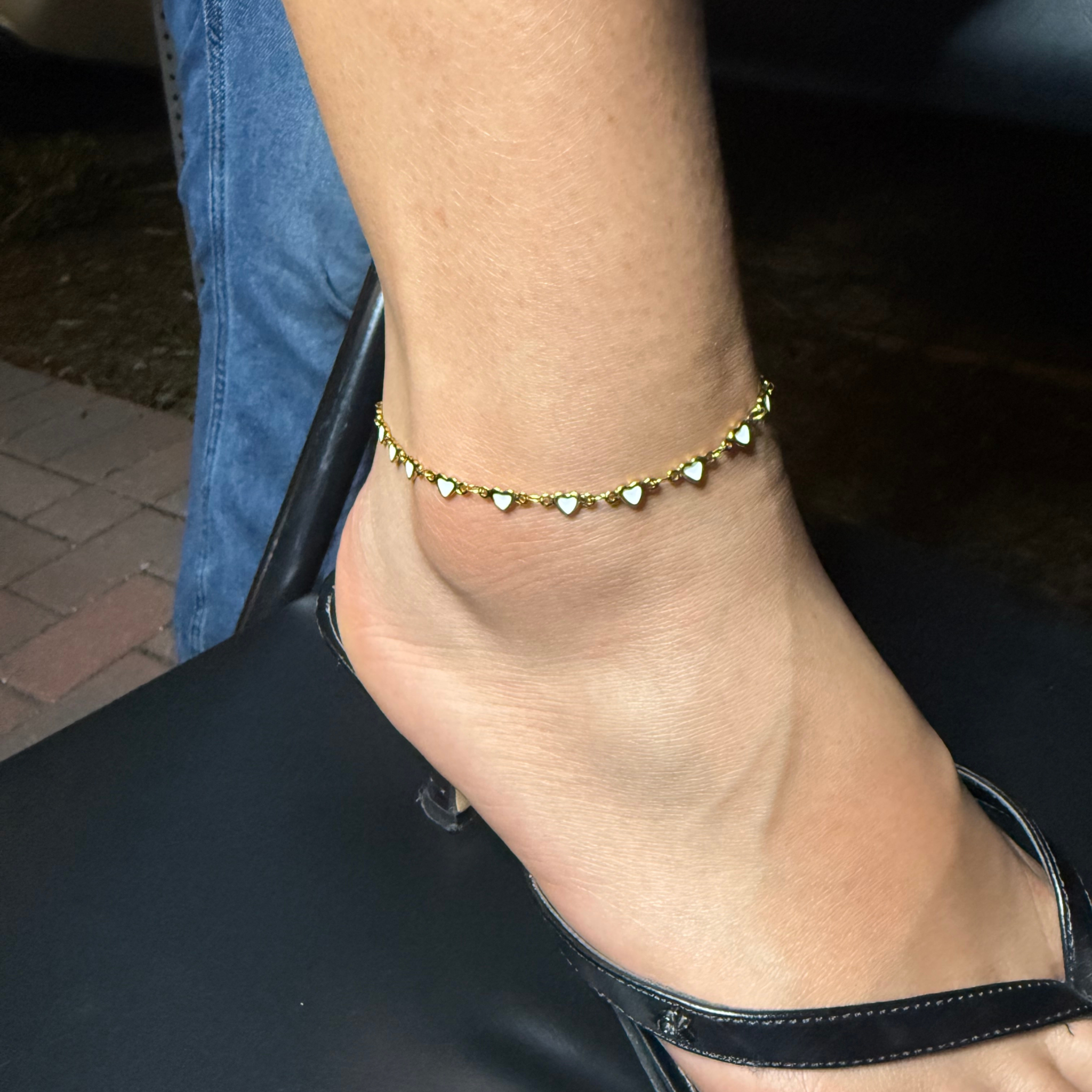 Gold heart anklet worn with a black sandal
