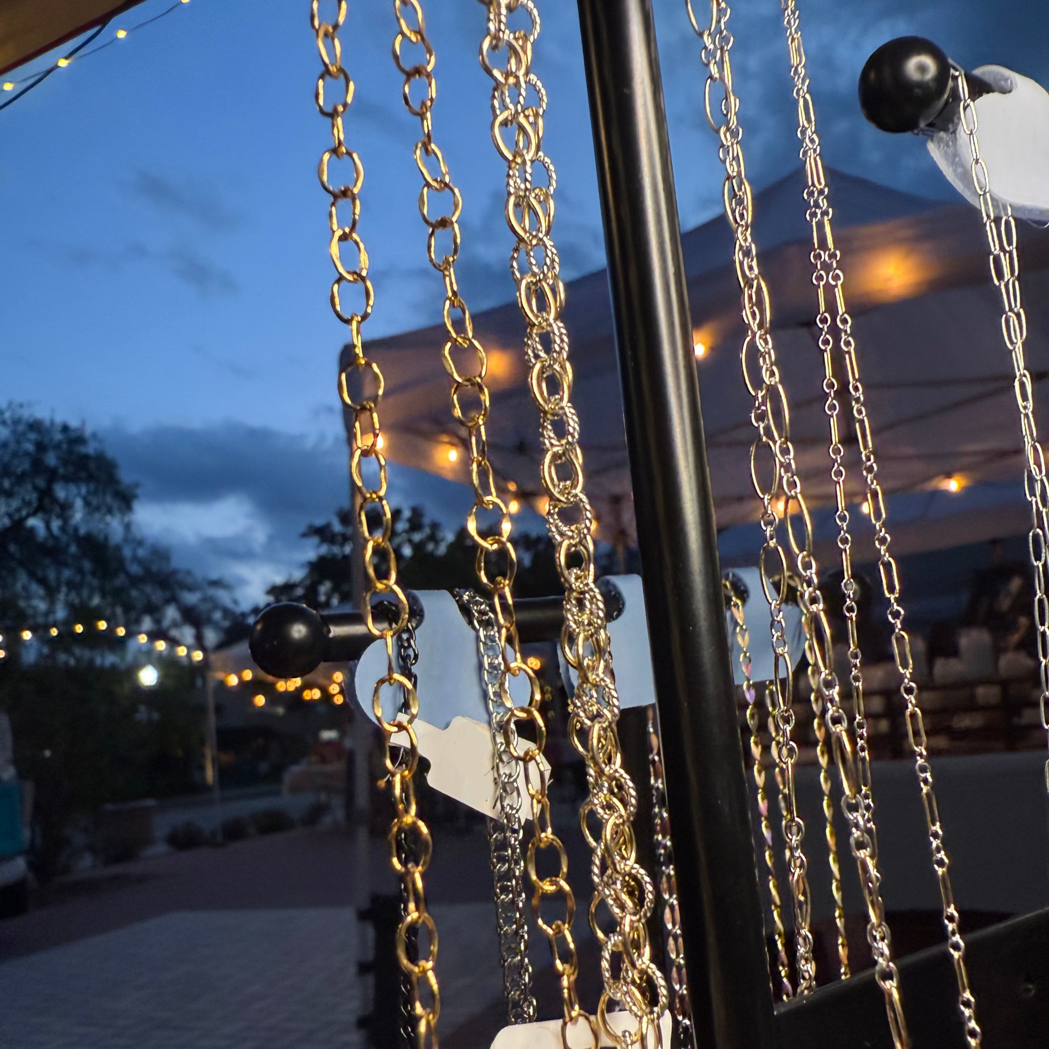 Gold and silver permanent jewelry chains displayed in evening light